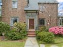 An inviting brick home featuring a classic front door, well maintained lawn, and beautiful flowering bushes in the yard at 1024 W Markham Ave, Durham, NC 27701