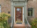 Classic brick home entrance featuring a wood and glass front door, with a historic building plaque, and professional landscaping at 1024 W Markham Ave, Durham, NC 27701