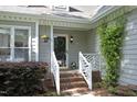 View of brick steps leading to the front porch, enhanced by climbing greenery, hanging and potted plants at 104 Silver Fox Ct, Cary, NC 27511