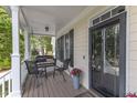 Inviting front porch featuring a cozy seating area with outdoor furniture and a black framed glass front door at 106 Kenneil Ct, Apex, NC 27502