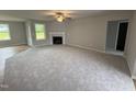 Bright living room with a fireplace, fan, neutral paint, and ample windows overlooking the yard at 115 Oakfield Trace Dr, Four Oaks, NC 27524