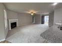 Spacious living room with a cozy fireplace, neutral carpet, and natural light at 115 Oakfield Trace Dr, Four Oaks, NC 27524
