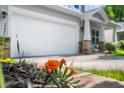 A ground-level shot shows a home's garage and porch from behind vibrant orange flowers at 15 White Spruce Ct, Durham, NC 27703