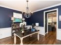 Sophisticated office space with dark blue walls, stylish chandelier, and chalkboard paint for creative expression at 204 Flint Point Ln, Holly Springs, NC 27540