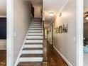 Elegant staircase with hardwood steps, white risers, and wooden handrail leading to the second floor at 204 Flint Point Ln, Holly Springs, NC 27540