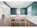 Elegant dining room with wainscoting, and wood table illuminated by chandelier, with large windows at 214 Thumper Way, Clayton, NC 27520