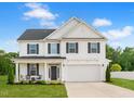 Charming two-story home featuring a well-manicured lawn, attached two-car garage, and inviting front porch at 214 Thumper Way, Clayton, NC 27520