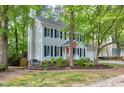View of the two-story home with grey siding, dark shutters, and lush, mature landscaping at 2205 Long And Winding Rd, Raleigh, NC 27603