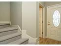Welcoming foyer with carpeted stairs, neutral walls, and a glimpse of wood flooring leading to the entrance door at 23 Great View Ct, Clayton, NC 27527