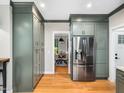 This kitchen features sage cabinets, stainless steel refrigerator and hardwood floors with dining room view at 2312 Laurelford Ln, Wake Forest, NC 27587