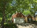 Shaded brick home featuring an attached two-car garage and lush landscaping at 2565 Bent Green St, Raleigh, NC 27614