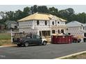 New construction home with visible framing and building materials, with a dumpster in the yard at 29 High Hampton Way, Fuquay Varina, NC 27526