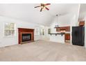 Open living room featuring a cozy fireplace, neutral carpeting, and easy access to kitchen at 300 Ravenstone Dr, Cary, NC 27518