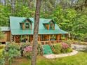 Inviting log home with green metal roof, lovely front porch, and mature landscaping at 3009 Pleasant Hill Church Rd, Siler City, NC 27344
