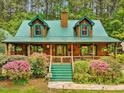Charming log home boasts a green metal roof, inviting porch, and beautiful flowering bushes at 3009 Pleasant Hill Church Rd, Siler City, NC 27344