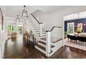 Bright foyer featuring hardwood floors, a staircase with white spindles and dark wood trim, and stylish light fixtures at 3312 Rock Creek Dr, Raleigh, NC 27609