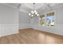 Elegant dining room boasts hardwood floors, wainscoting, coffered ceiling, chandelier, and large windows at 3529 Bailey Lake Dr, Fuquay Varina, NC 27526