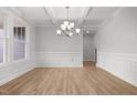 Bright dining area featuring hardwood floors, wainscoting, coffered ceilings, and a modern chandelier at 3529 Bailey Lake Dr, Fuquay Varina, NC 27526