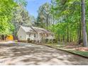 Cozy single-story house with covered porch, set on a gravel driveway, surrounded by lush trees at 3607 Springhollow Ct, Efland, NC 27243