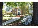 Traditional brick home with manicured landscaping, walkway and mature trees creating a park-like setting at 4101 John S Raboteau Wynd, Raleigh, NC 27612