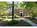 Brick home with a landscaped yard, a pathway leading to the front door, and surrounded by mature trees at 4101 John S Raboteau Wynd, Raleigh, NC 27612