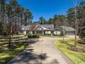 Expansive gray home with manicured lawn, circular driveway, and attached three-car garage against a backdrop of mature trees at 464 Rosemont Dr, Durham, NC 27713