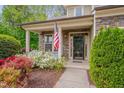 Inviting front porch with stone accents, decorated with flowers, and American flag at 504 Applecross Dr, Mebane, NC 27302