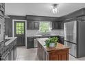Charming kitchen with dark cabinets, stainless steel refrigerator, tile floors, and island with plants at 615 Beaver Creek Rd, Apex, NC 27502