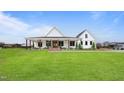 Beautiful modern farmhouse with a sprawling green lawn, featuring a classic covered porch at 6185 Nc-50, Benson, NC 27504