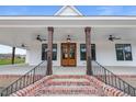 Charming front porch with wood columns, brick stairs, and a stylish wooden double-door entryway at 6185 Nc-50, Benson, NC 27504