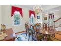 Formal dining room featuring a chandelier, large windows with red drapes, and a wood table at 6245 Hampton Ridge Rd, Raleigh, NC 27603