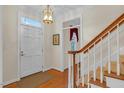 Elegant foyer featuring hardwood floors, a stylish light fixture, and staircase with wooden handrail at 6245 Hampton Ridge Rd, Raleigh, NC 27603