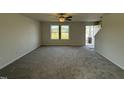 Spacious living room features neutral carpeting, a ceiling fan, and a view of the entryway and staircase at 63 Coharie Dr, Lillington, NC 27546