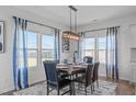 A dining room featuring a wood table set for six, complemented by bright, sunlit windows and stylish curtains at 76 Arlie Ln, Lillington, NC 27546
