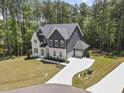 Aerial view of a two-story home with a long driveway, attached garage, manicured lawn, and wooded surroundings at 8237 Baronleigh Ln, Wake Forest, NC 27587