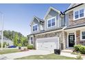Charming townhouse with a stone facade, green siding, and a two-car garage at 8426 Garnet Rose Ln, Raleigh, NC 27615