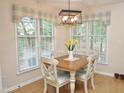 Cozy dining area with a wooden table, four chairs, a modern light fixture, and a large window with attractive blue accents at 8712 Attingham Dr, Raleigh, NC 27615
