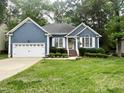Charming single-story home featuring a blue exterior, white trim, a well-manicured lawn, and an attached two-car garage at 8712 Attingham Dr, Raleigh, NC 27615