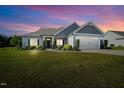 Inviting single-story home with a well-kept lawn and attached two-car garage under a beautiful sunset at 93 Fallingbrook Dr, Kenly, NC 27542