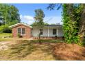 Single-story home with brick and white siding surrounded by lush greenery and mature trees at 108 Deepwood Cir, Garner, NC 27529