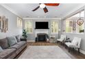 Cozy living room with a fireplace, modern ceiling fan, and views through white-shuttered windows at 1209 Shasta Daisy Dr, Wake Forest, NC 27587