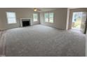 Bright, open living room with a fireplace, plush carpet, and lots of natural light from several windows at 139 Oakfield Trace Dr, Four Oaks, NC 27524