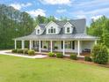 Beautifully landscaped home with a metal roof and a spacious front porch featuring a relaxing swing at 140 Crystal Pl, Benson, NC 27504