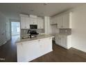 Bright kitchen featuring white cabinets, center island, and complementary backsplash at 1569 Wendell Valley Blvd, Wendell, NC 27591