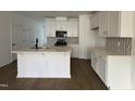 Modern kitchen with white cabinets, island, quartz counters and stylish backsplash at 1569 Wendell Valley Blvd, Wendell, NC 27591