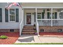 Inviting front porch with brick stairs, white railings, and dark green shutters, creating a cozy entrance at 1576 Cheves Rd, Zebulon, NC 27597