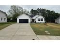 A white one-story home with a black garage door, concrete driveway, and grassy front yard at 163 Oakfield Trace Dr, Four Oaks, NC 27524