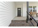 Close-up of the front porch entrance, featuring a rustic bench, black railings, and a stylish front door at 180 Packhouse Ct, Angier, NC 27501