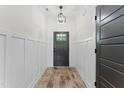 Bright hallway with wood floors, wainscoting, and a stylish pendant light fixture above the front door at 180 Packhouse Ct, Angier, NC 27501