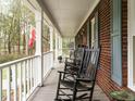 Inviting front porch with rocking chairs, brick facade, and white columns at 204 Wiley Oaks Dr, Wendell, NC 27591